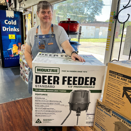Benton's staff member holding a seasonal deer feeder box inside the store.